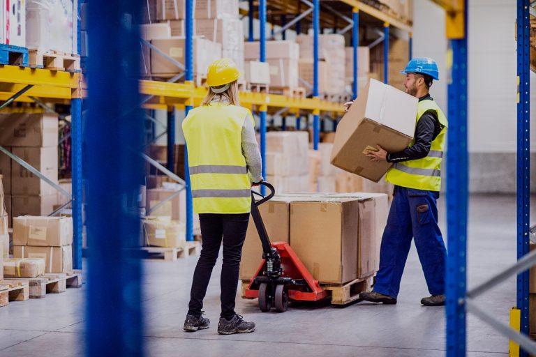 Young workers in a warehouse loading or unloading a pallet truck.